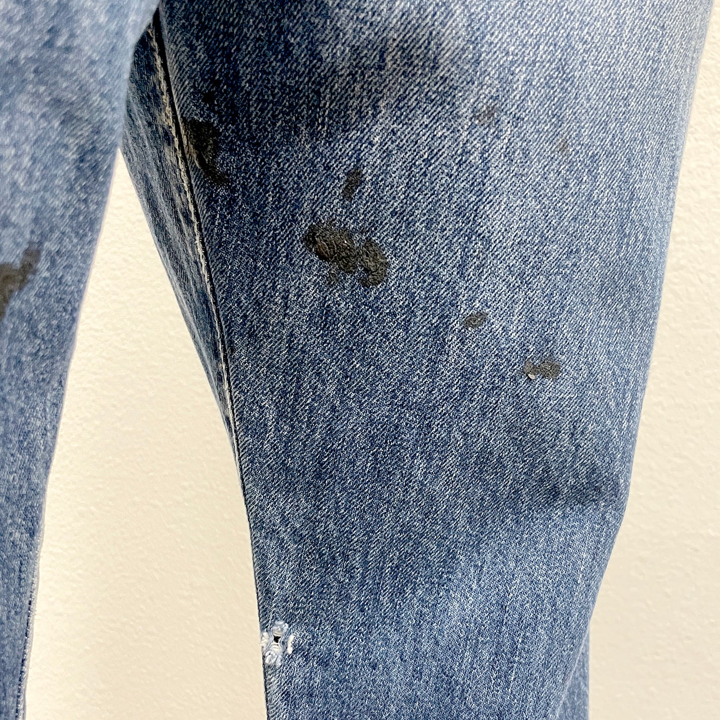Close-up of a pair of blue jeans with visible wear and tear on a beige background