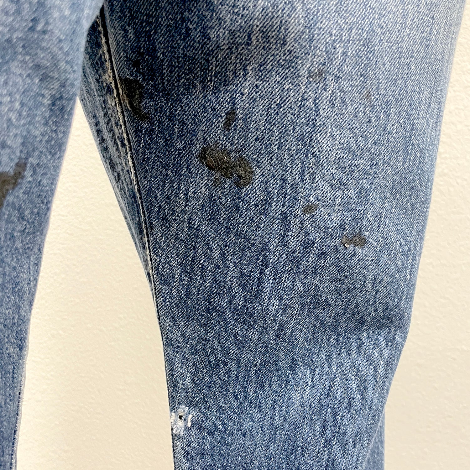 Close-up of a pair of blue jeans with visible wear and tear on a beige background
