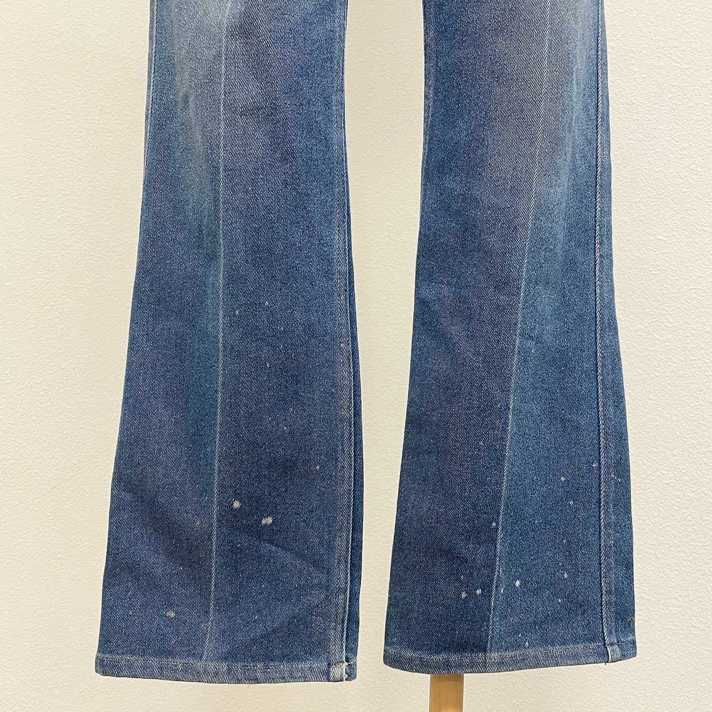 Pair of blue jeans on a beige background with bleach spots at hems