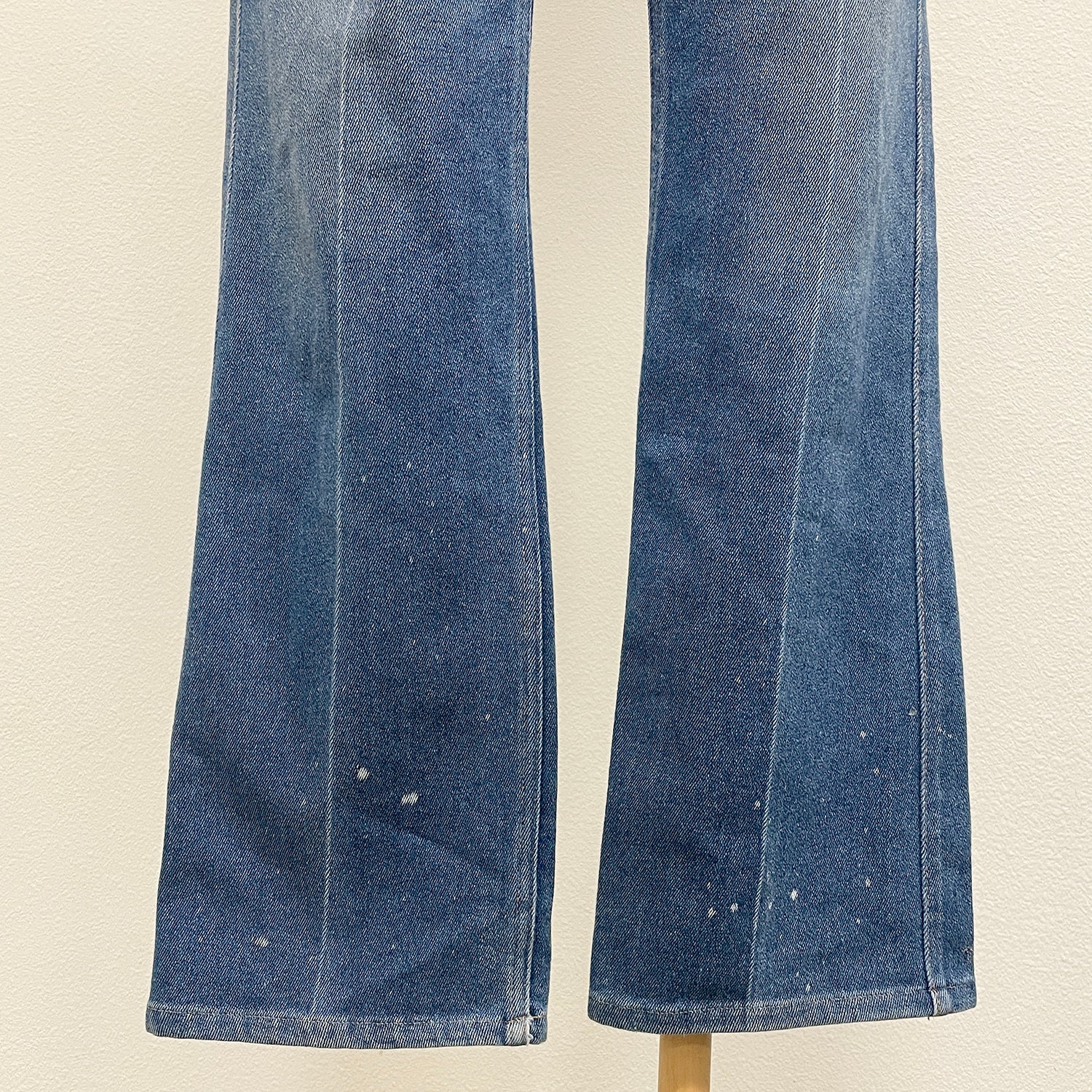 Pair of blue jeans on a beige background with bleach spots at hems
