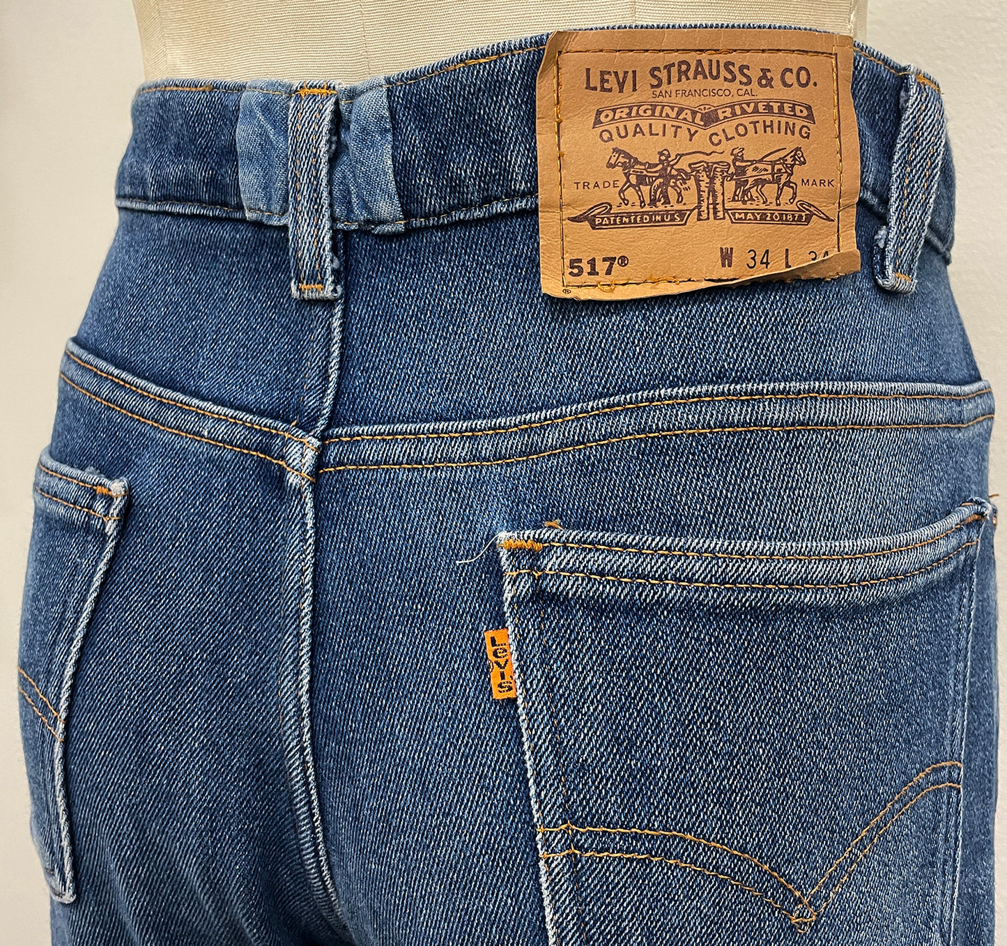 Close-up of blue jeans with Levi's label on a beige background with center back waistband repair