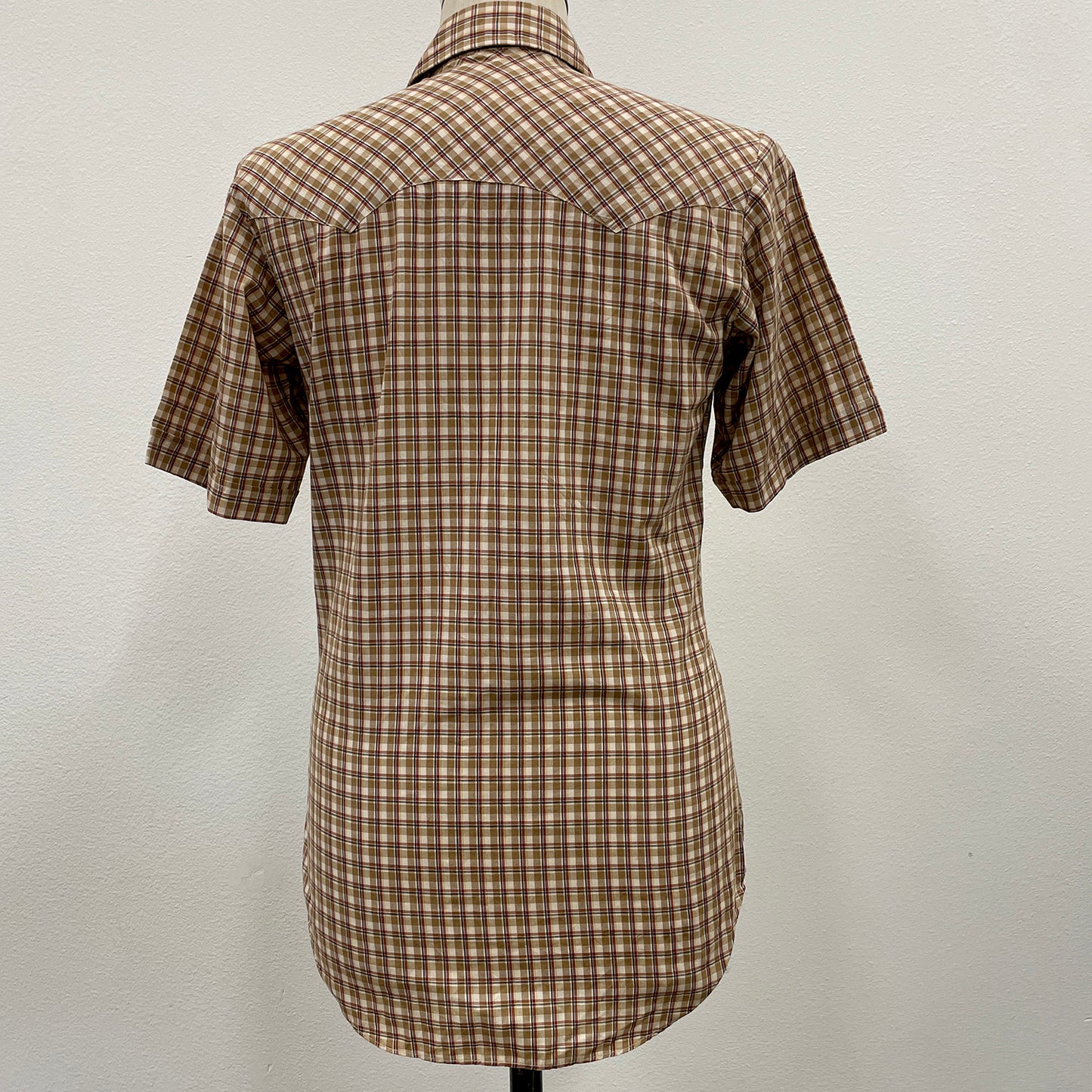 Khaki plaid shirt on a mannequin against a plain background