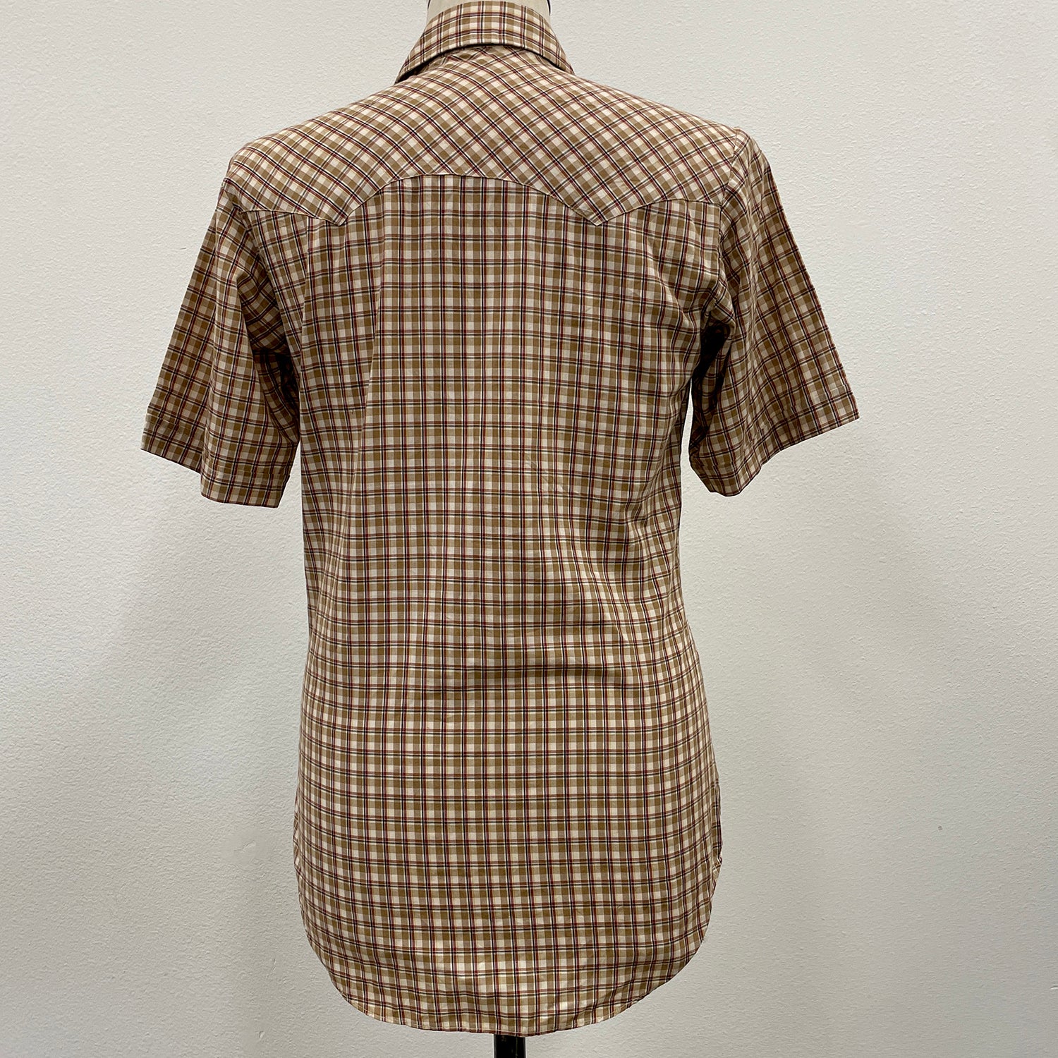 Khaki plaid shirt on a mannequin against a plain background