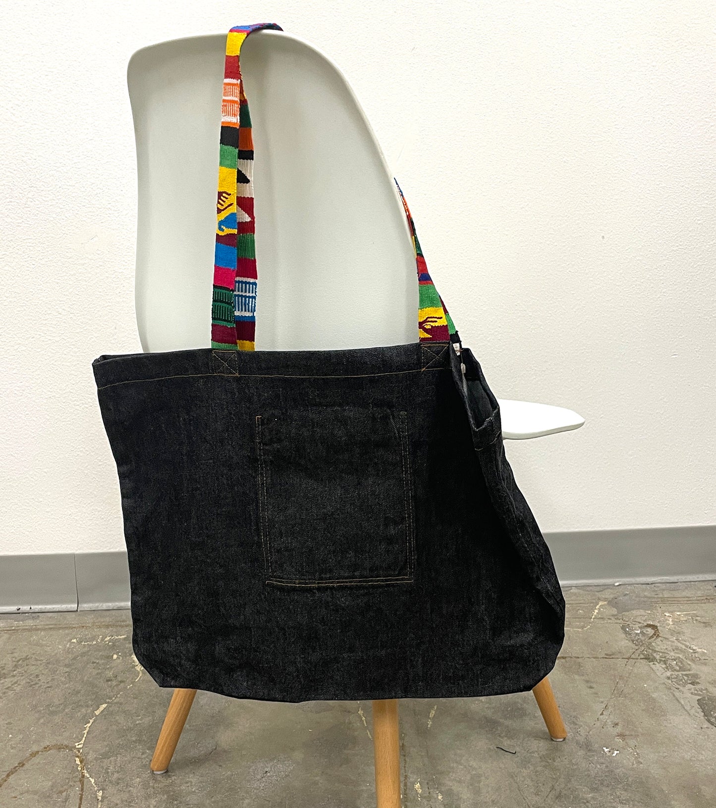 Black tote bag with colorful strap on a mannequin against a white background