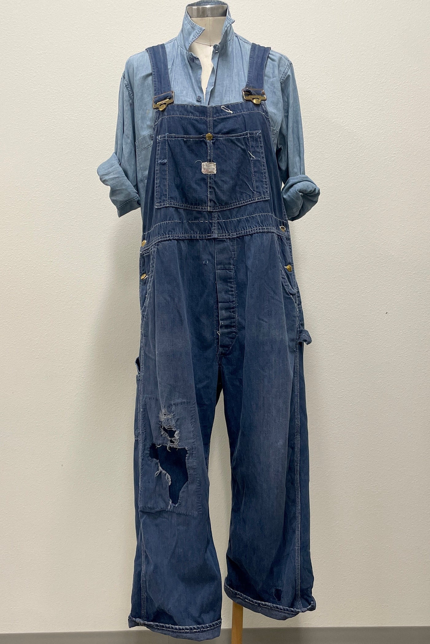 Blue denim overalls on a mannequin against a plain background
