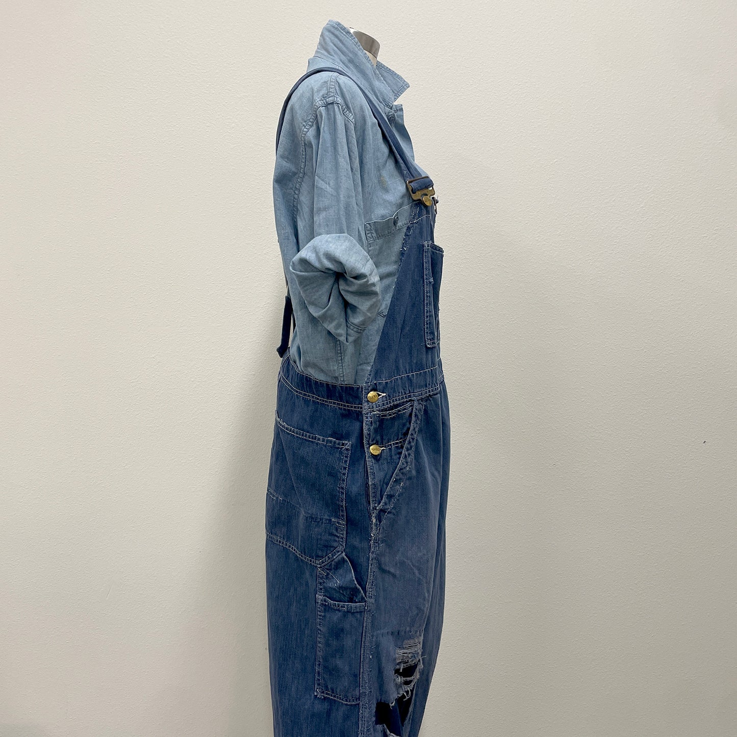 Blue denim overalls on a mannequin against a plain background