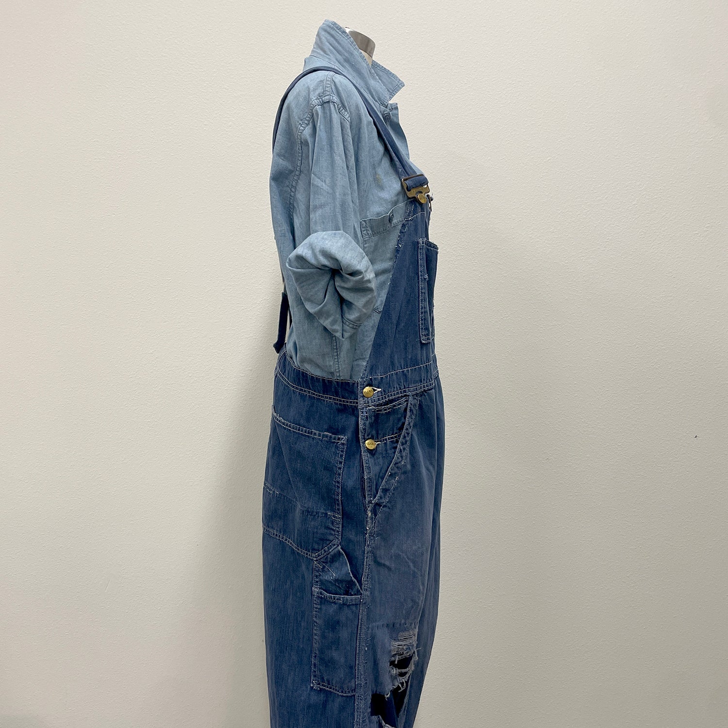Blue denim overalls on a mannequin against a plain background
