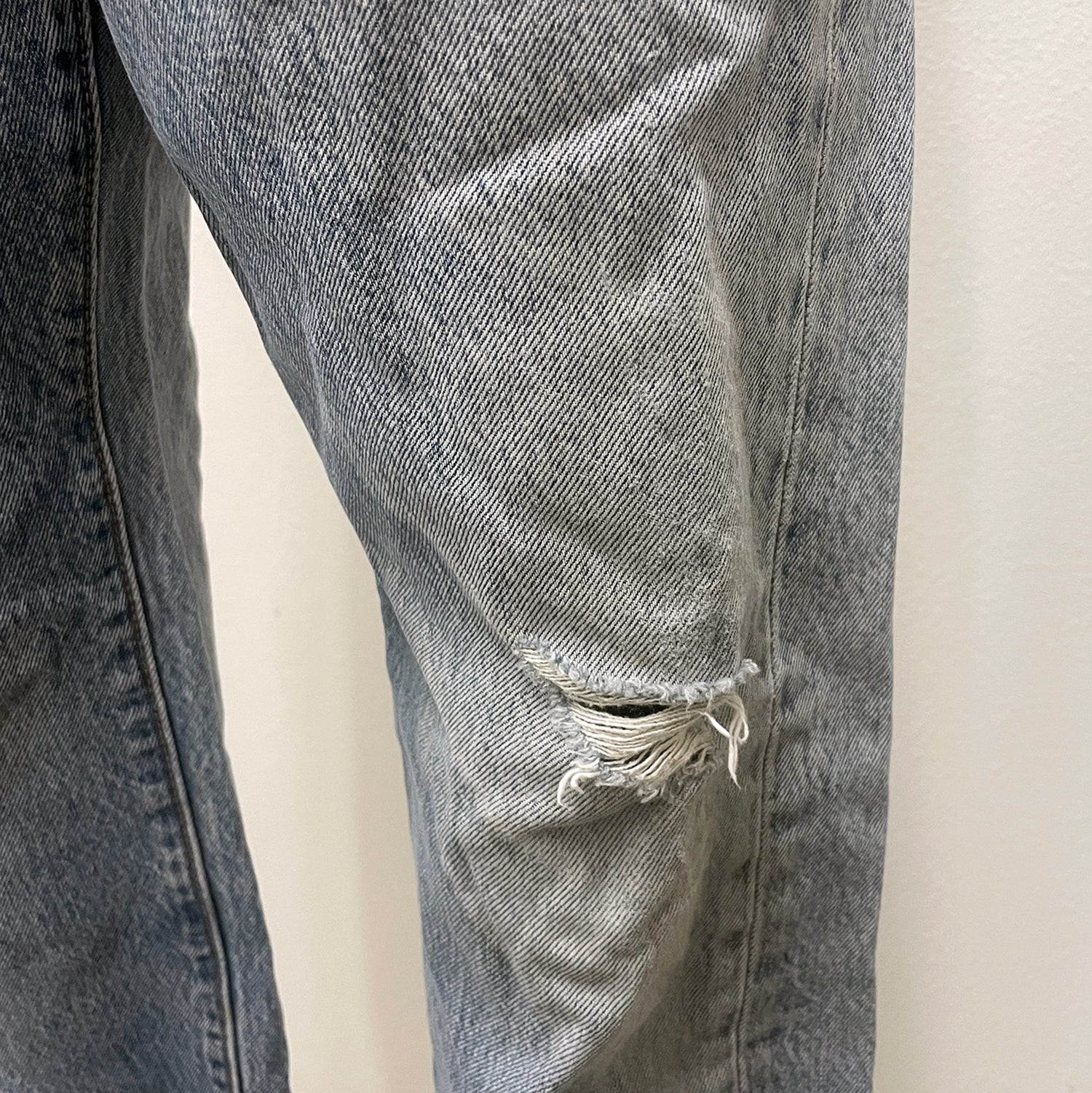Close-up of a distressed denim jeans with a white background