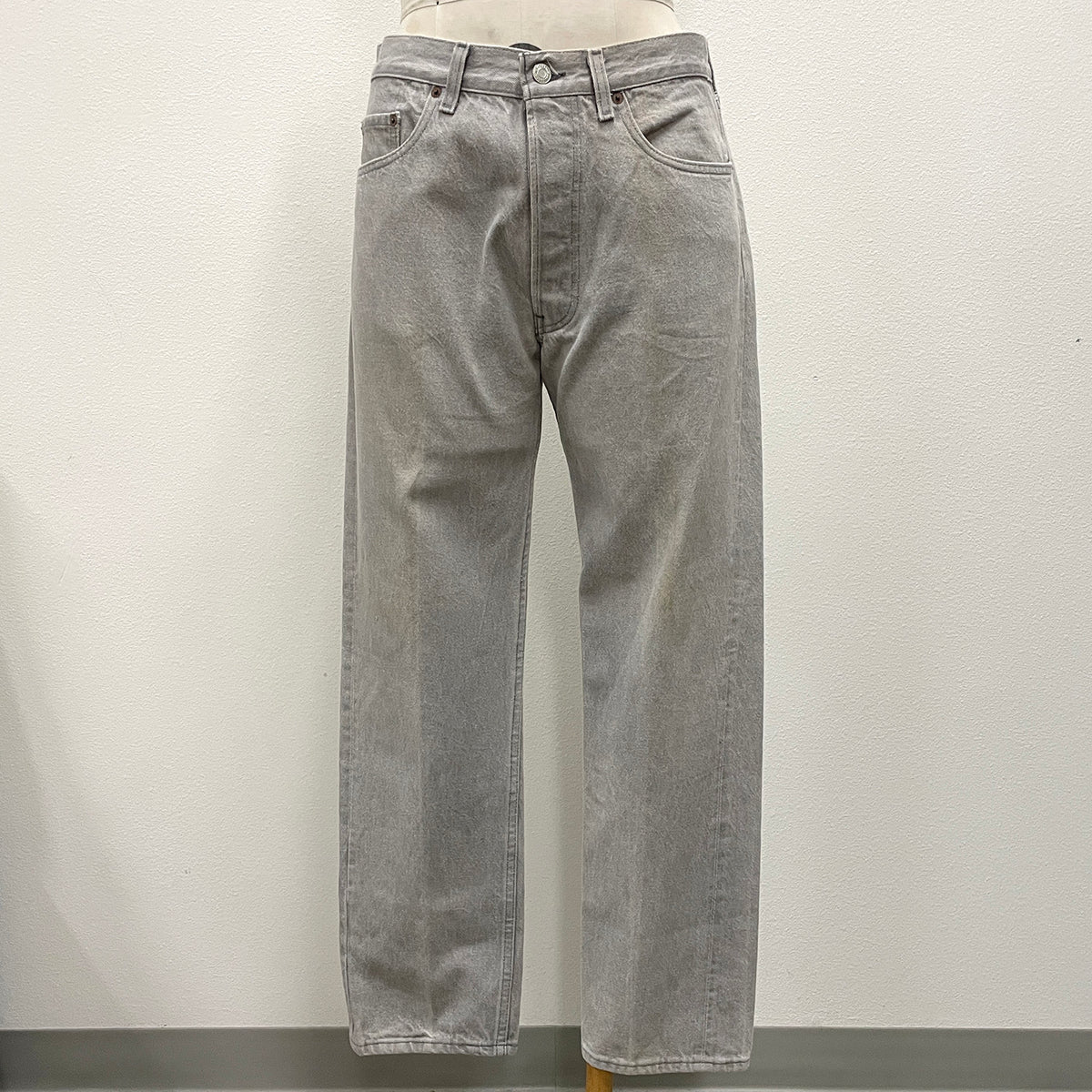 Light gray washed denim jeans displayed on a mannequin torso against a plain off-white wall.