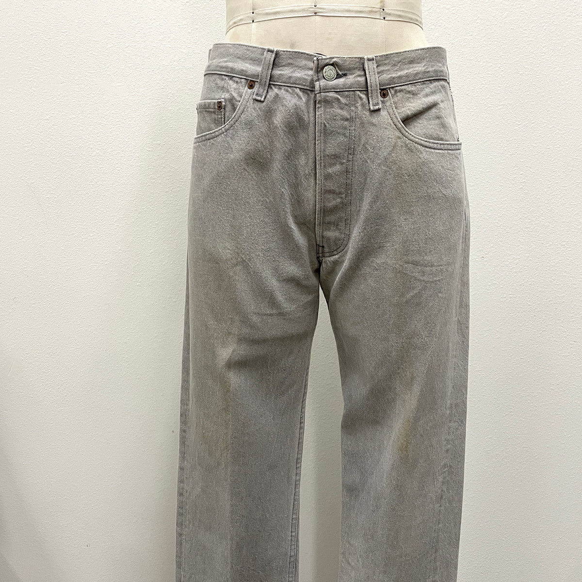 Light gray washed denim jeans displayed on a mannequin torso against a plain off-white wall.